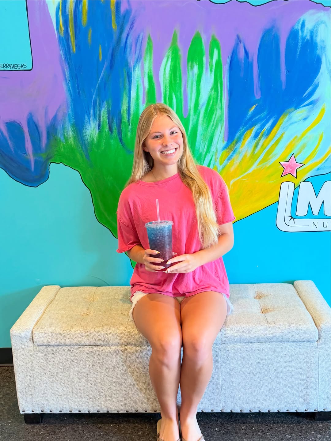 An Imperial Nutrition guest with a crafted tea in front of the Texas mural